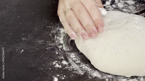 Close up of female hands kneading and preparing yeast dough on the table, making round ball for resting 