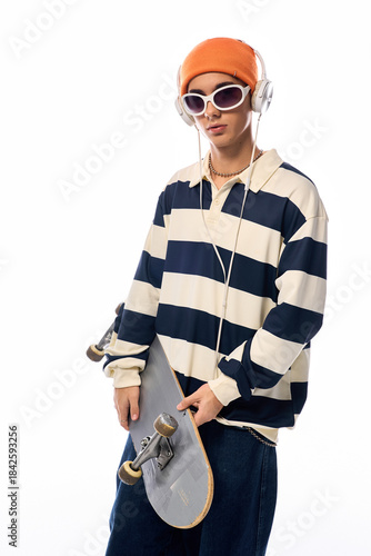 Fashionable teen with a skateboard poses against a white backdrop