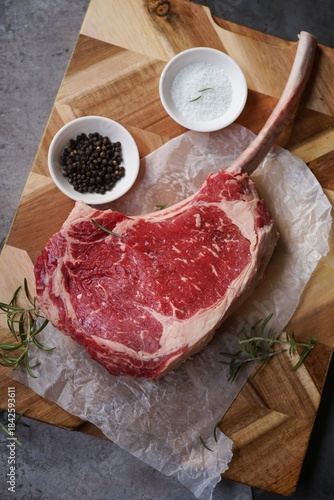 Raw uncooked Tomahawk steak with bone with salt and pepper