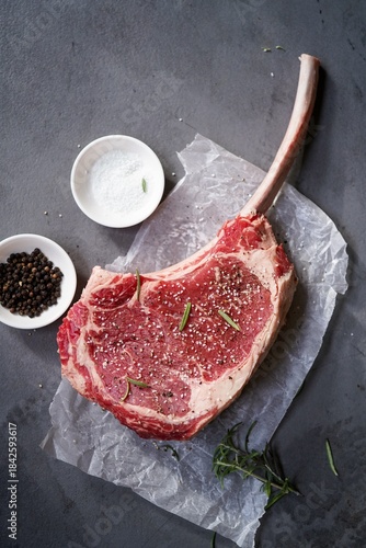 Raw uncooked Tomahawk steak with bone with salt and pepper
