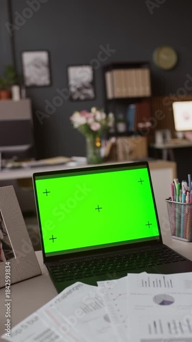 Wallpaper Mural Vertical shot of black laptop with green screen, papers with diagrams and office supplies on top of table in office Torontodigital.ca