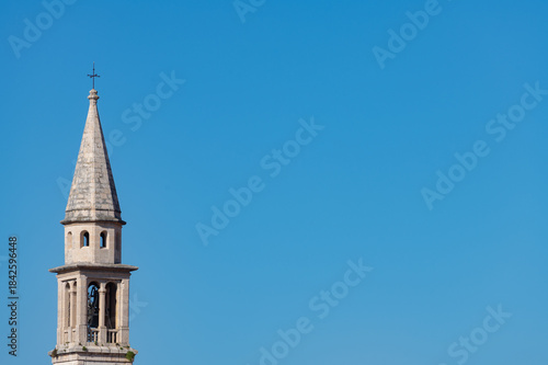The bell tower of a Catholic church against a blue sky in the Montenegrin town of Budva.