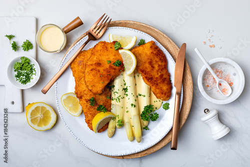 White asparagus with fried schnitzel, lemon and hollandaise sauce