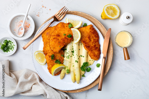White asparagus with fried schnitzel, lemon and hollandaise sauce