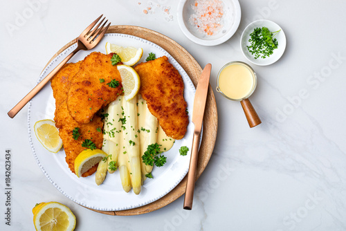 White asparagus with fried schnitzel, lemon and hollandaise sauce