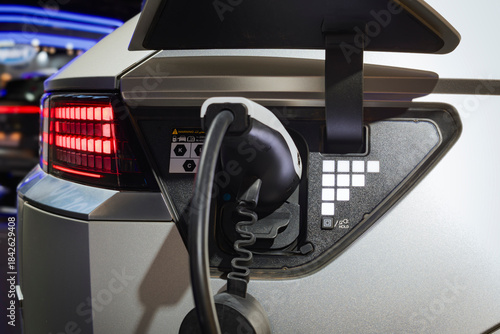 Charging port of the electric vehicle showing connected plug, pixel pattern LED indicators, and illuminated rear light cluster.