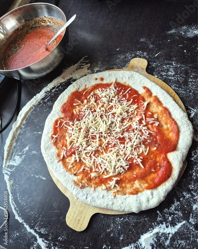 An evocative image of a homemade pizza made with tomato sauce, mozzarella, and oregano, ready to be baked.
