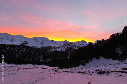 Sunset in the high mountains with a view of the snow-capped peaks and the pink and red sky