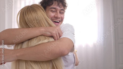 Happy couple sitting on the bed and smiling with excitement while looking at a positive pregnancy test