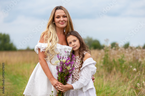 Mother and daughter share a joyful moment in a field with wildflowers on a sunny day