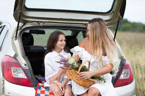 Mother and daughter share a joyful moment while picking wildflowers during a sunny day in the countryside