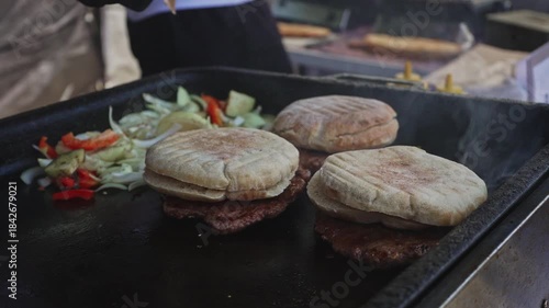 Fresh hamburgers cooking on a street grill.