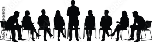 Silhouetted group seated in circle with standing speaker leading discussion for meeting, support session, teamwork, communication, and collaboration