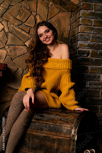 Beautiful girl sitting next to the fireplace. Luxury interior decorated for Christmas with fir branches and toys