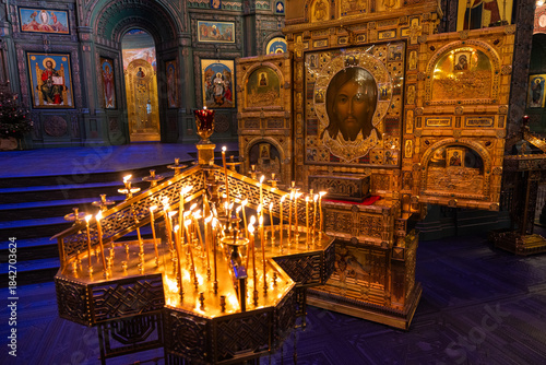 View of golden icons gleaming in the soft light of flickering candles, illuminating the ornate interior of a Russian Orthodox church, Kubinka, Moscow Oblast, Russia.