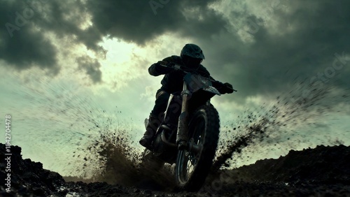 A motocross rider in silhouette splashes mud and water while riding a dirt bike aggressively in dark, dramatic, and stormy weather conditions.