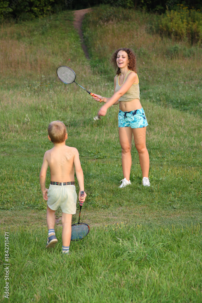 Obraz premium A young girl is playing tennis with a boy. The girl is wearing a blue and white striped shirt and blue shorts