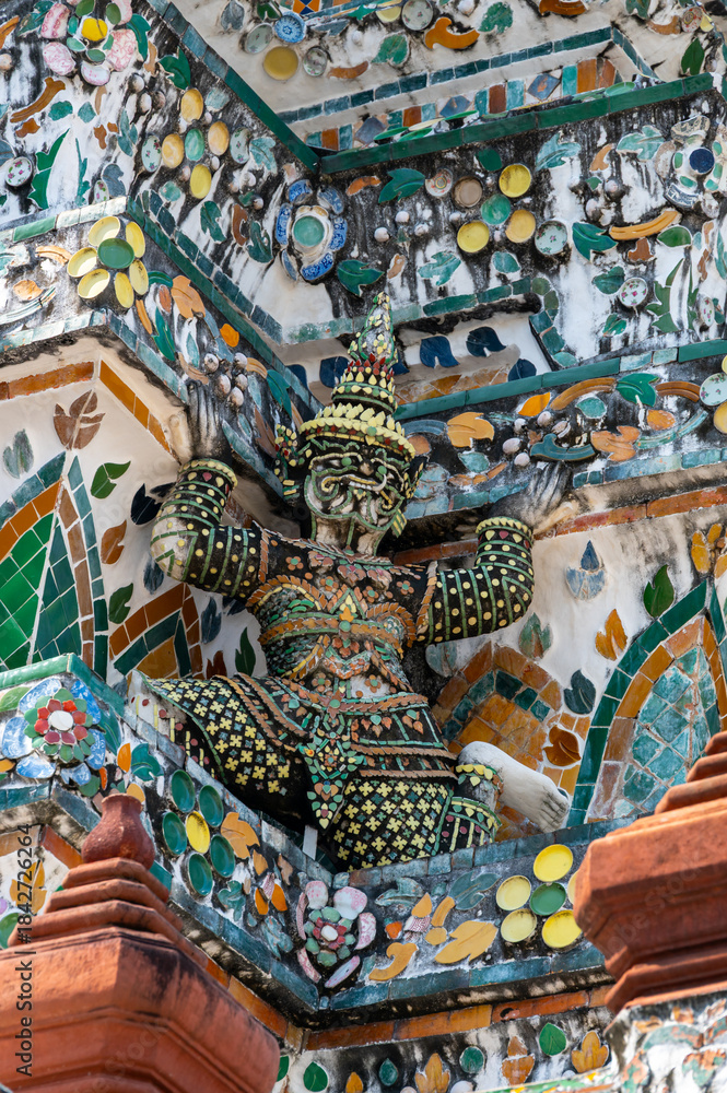 Fototapeta premium Detailed view of the ornate towers of Wat Arun in Bangkok, Thailand, showcasing rich ceramic floral patterns, sculpted figures, and intricate decorations under bright daylight.