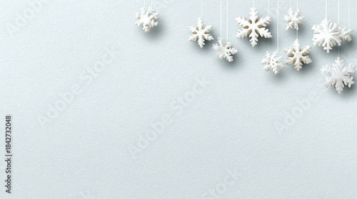 Delicate white snowflakes hanging against a light blue textured background