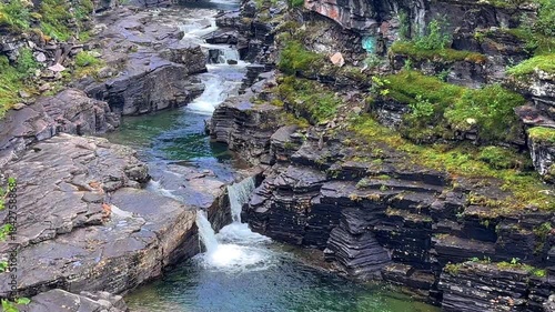 Creek in the wilderness of  Norway framed by lush green grass