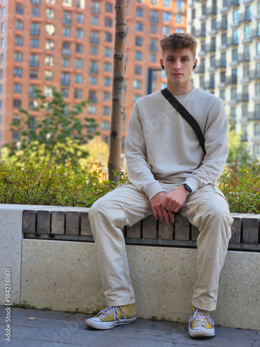 Bild auf Leinwand Man wearing a white shirt and pants sits on a bench