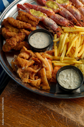 A mouthwatering seafood platter filled with golden fried shrimp, crispy fish, and perfectly fried potatoes sits on a table. The scene celebrates fresh flavors and sunny moments