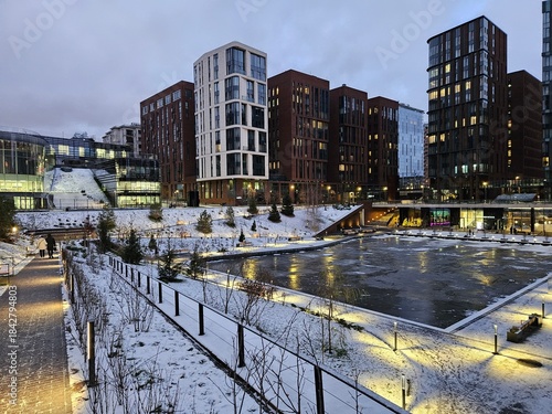 Photography Snowy city street with a large building near pond