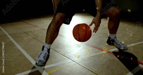 Male basketball player starting through-legs dribbling ball on court training star over right leg
