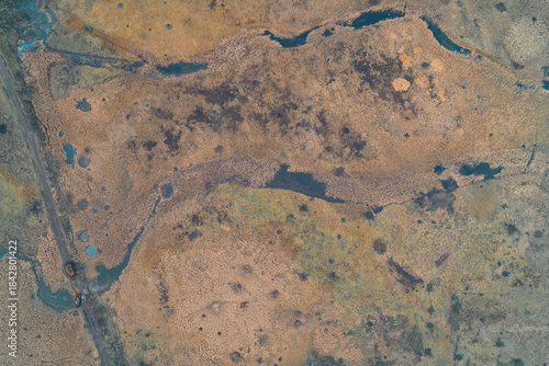 Fotografi Abstract natural pattern of vast marshlands and swamp terrain with winding blue