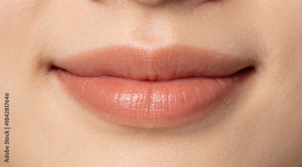 Obraz premium Extreme close-up of a delicate smile with soft lip curves and subtle natural texture. Minimal composition with clean studio lighting, detailed and realistic macro aesthetic