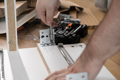 Wallpaper Mural Person's hands meticulously assemble new flat-pack furniture, expertly using a screwdriver to secure a metal bracket, depicting home improvement and DIY projects Torontodigital.ca