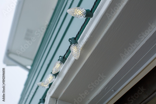 holiday christmas lights hang on side of blue house in winter