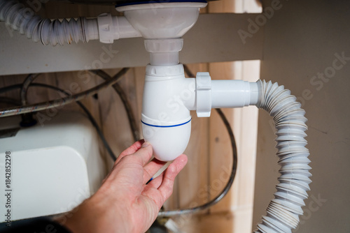 Fotografi Carefully Hand Adjusting the Plumbing Drain Right Underneath the Kitchen Sink wi