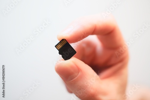 hand with flash memory. hand holding micro sd card. Caucasian hand holding a microSD memory card.