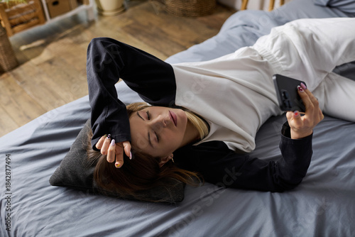 Billede på lærred Young woman embraces bed rotting in her cozy apartment during a relaxing day alo