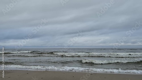 Calm sea waves breaking near the shoreline beneath a cloudy sky. Natural ocean sounds, peaceful coastal atmosphere, minimalist seascape. 4K relaxing nature video.