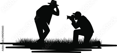 Two photographers capturing a moment in silhouette against a grassy backdrop