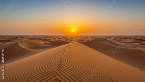 Fototapeta Naklejka Na Ścianę i Meble -  Sunset over the desert with sand dunes and footprints, capturing the tranquility of the arid landscape. Nature and landscape scene, warm colors, serenity.