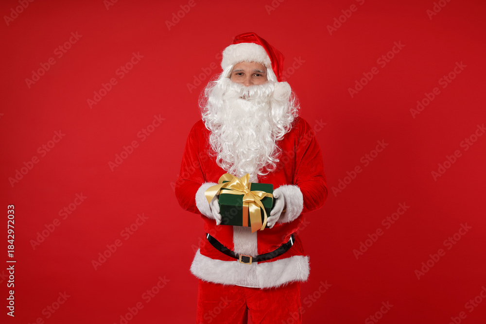 Naklejka premium Santa Claus with Christmas gift on red background