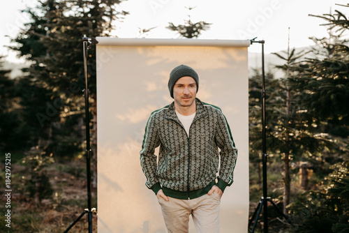 Mann in grüner Weste vor beigem Studiohintergrund in freier Natur