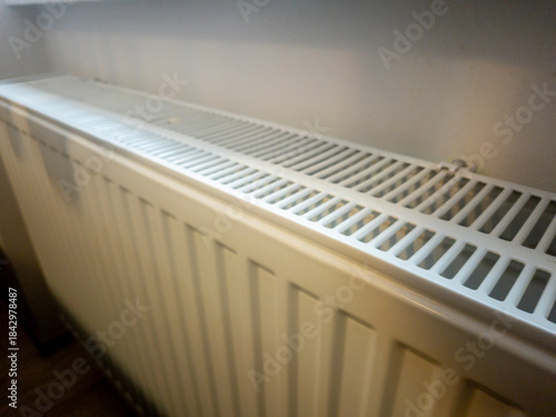 Wallpaper Mural Close-up of a modern white radiator installed in a room, providing heating. The sleek lines and grid pattern of the cover suggest efficiency and contemporary design, ideal for interior warmth. Torontodigital.ca