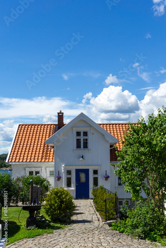 Traditional White Wooden House with Blue Door and Cobblestone Path in Son Norway