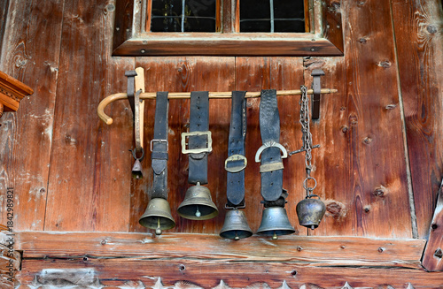 old cowbells on leather belts hanging from a stick as a Bavarian style alpine cabin deco