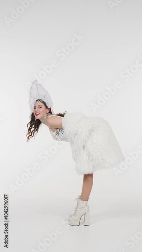Elegant woman in sparkling snow queen costume performs graceful dance on white background. Festive winter video content for Christmas, New Year events, fashion shows and seasonal marketing
