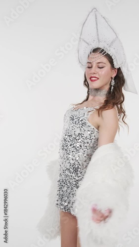 Elegant woman in sparkling snow queen costume performs graceful dance on white background. Festive winter video content for Christmas, New Year events, fashion shows and seasonal marketing
