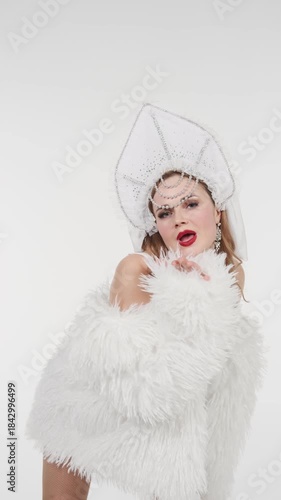 Elegant woman in sparkling snow queen costume performs graceful dance on white background. Festive winter video content for Christmas, New Year events, fashion shows and seasonal marketing
