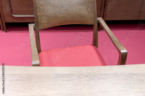 Wooden desk and chair with red seat on the red floor in the living room, close-up