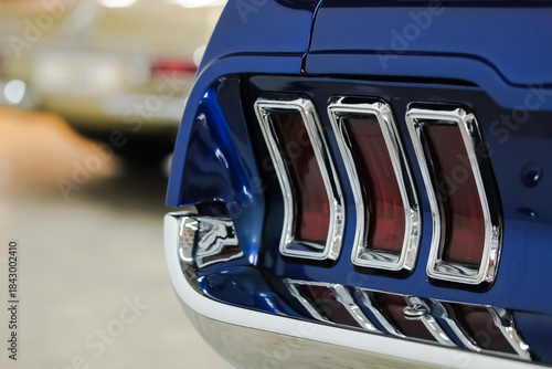 Tail light and bumper close-up details of a blue vintage American Car. Rear view of a classic car with copy space.