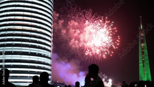 City skyline celebration with colorful fireworks lighting the night sky as people watch festive urban New Year event