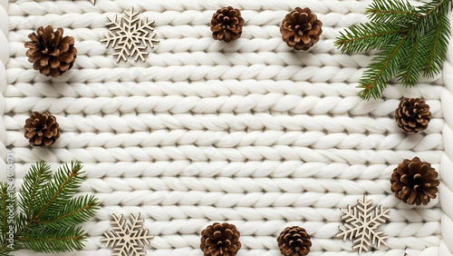 Cozy Christmas flat lay with chunky white knit texture, pinecones, fir branches and wooden snowflakes, winter background with copy space